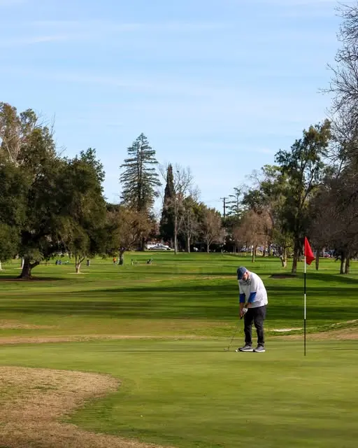 Golfer putting on green with red flag at William Land Golf Course Sacramento